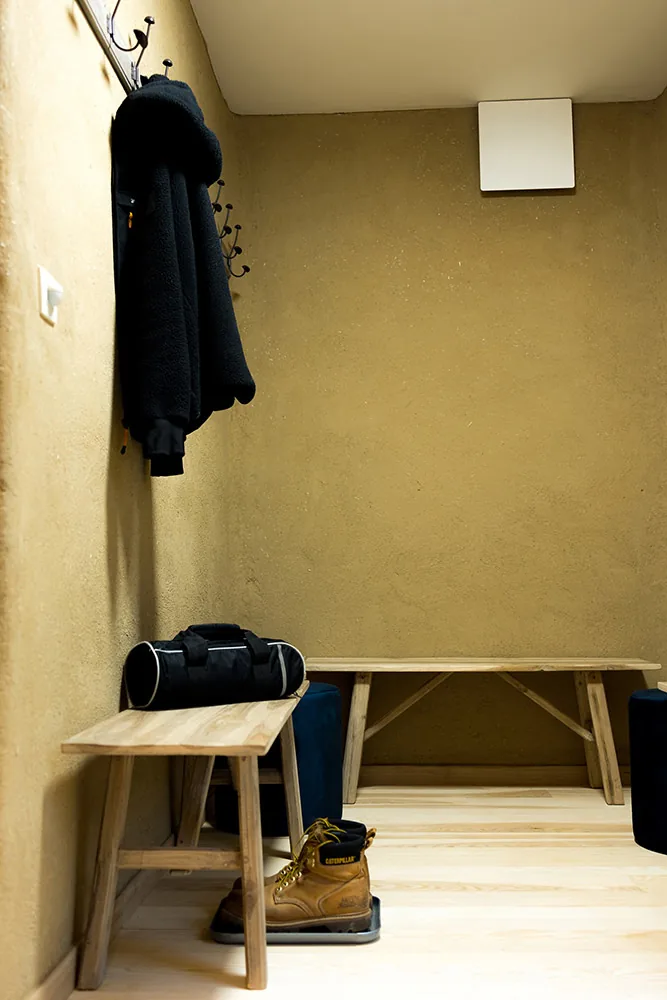 Le vestiaire de la salle : patères, banc en bois et mur en enduit naturel